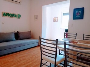 A living room with a sofa, dining table, chairs, and a kitchen area. - One Bedroom Apartment with Terrace (Rovinj)