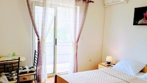 A bedroom with a bed, a chair, a table, and a lamp. - Double Room with Balcony (Rovinj)