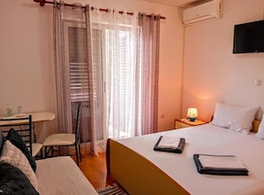 A hotel room with a bed, bedside lamp, and a small table with a chair. - Double Room with Balcony (Rovinj)