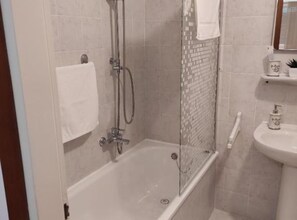 Ein Badezimmer mit einer gläsernen Duschkabine, einer weißen Badewanne, einem Waschbecken und einem Spiegel darüber.