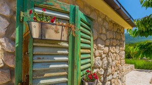 A stone building with a window featuring green shutters and a metal flower pot. - Villa with swimming pool (Vrgorac)
