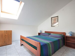 A bedroom with a bed, a wardrobe, a nightstand, a lamp, and a painting on the wall. - One Bedroom Apartment with small Balcony (Umag)