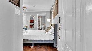 Un couloir étroit mène à une chambre à coucher qui contient un lit, une table de chevet et un miroir.