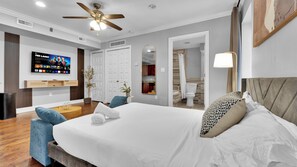 Une chambre d’hôtel équipée d’un lit, d’une télévision, d’un ventilateur de plafond, d’une salle de bain et d’un coin repas.