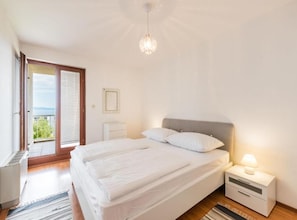 A bedroom with a bed, bedside table, and a view of the outdoors. - Comfort Three Bedroom Apartment with Terrace and Sea VIew (Split)
