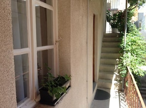 Ein Balkon mit Fenster, einem Blumentopf und einer Treppe.
