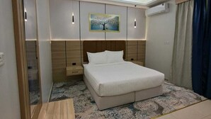 Une chambre à coucher moderne, avec un lit, des tables de chevet, un miroir, un appareil de climatisation et un tableau accroché au mur.