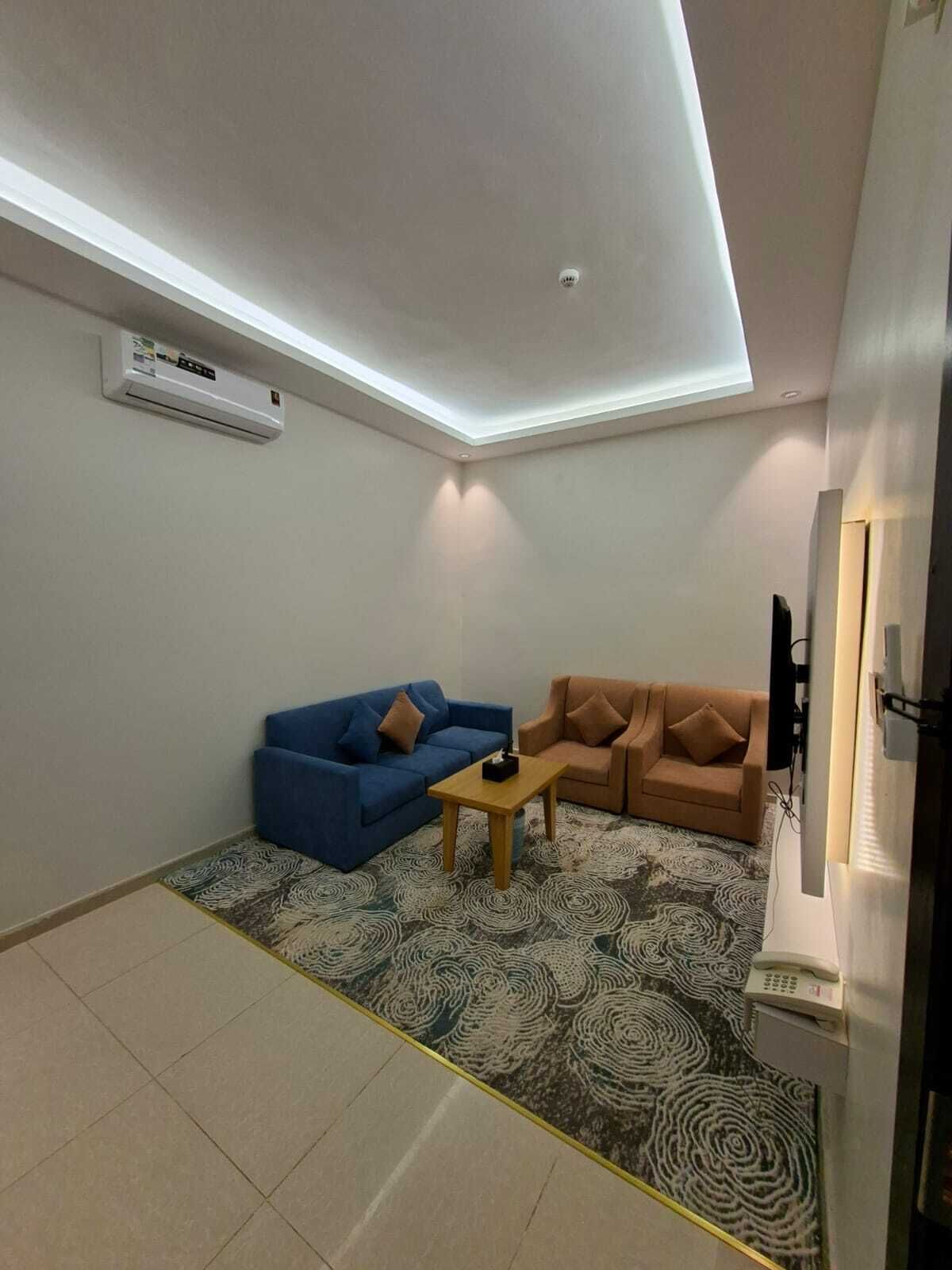 A small living area with a blue and brown sofa set, a small table, and a patterned rug.