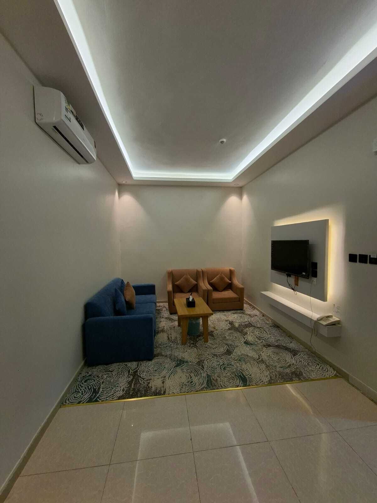 Una sala de estar moderna con un televisor de pantalla plana, dos sofás, una mesa de centro y una alfombra estampada.