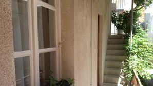 Een balkon met een raam, een bloempot en een trap.