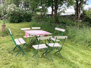 A picnic setup with a table and chairs in a grassy area, surrounded by trees and bushes. - 5 Person Holiday Home in Bastad (Bastad)