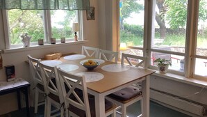 A dining area with a table, chairs, a bowl of lemons, and a window with a view of greenery. - 5 Person Holiday Home in Bastad (Bastad)