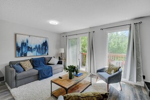 A modern living room with a grey sofa, a coffee table, and a painting on the wall.