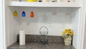 Eine Küche mit weißen Schränken, einer Granit-Arbeitsplatte und verschiedenen Küchenutensilien, darunter eine gelbe Schüssel, eine Küchenpapierrolle und eine Vase mit Blumen.
