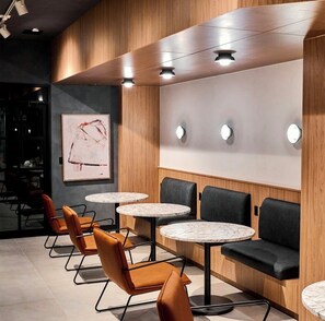 Un interior moderno con mesas redondas, asientos acolchados, paneles de madera e iluminación empotrada.