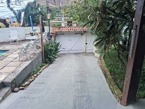 Ein gepflasterter Weg führt zu einem einkuppeligen Eingangstor, umgeben von Grünflächen und einer Steinmauer.