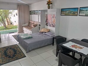 Ein Zimmer mit einem Bett, einem Schreibtisch, einem Stuhl, einem Tisch und einem Fenster.