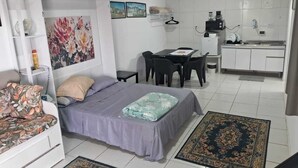 A compact living space with a bed, a small table, a kitchenette, and a seating area. - Studio 81 (Rio de Janeiro)