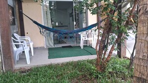 A hammock, white plastic chairs, and a small garden area with grass and a tree. - Studio 81 (Rio de Janeiro)