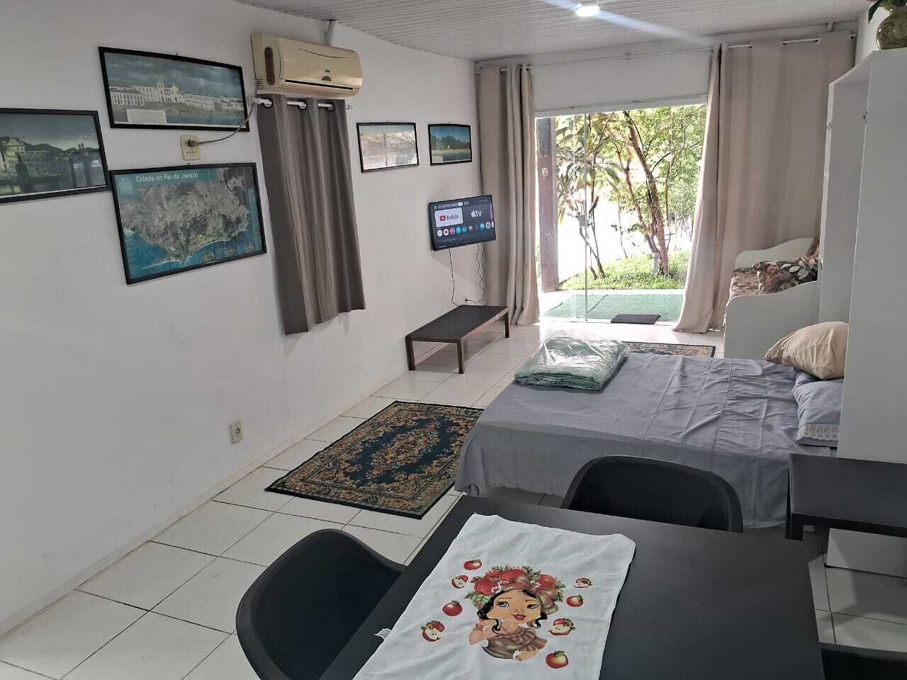 A room with a bed, a desk, a chair, a TV, and a window with curtains.