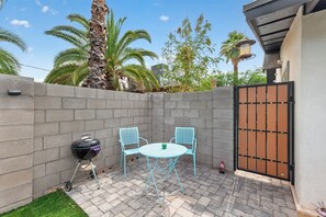 Eine Terrasse mit Grill, zwei Stühlen und einem Tisch.