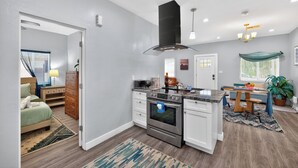 Uma cozinha moderna com ilha central, forno embutido e armários brancos.
