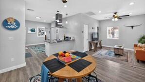 Uma sala de estar moderna com área de jantar, cozinha e um ventilador de teto.