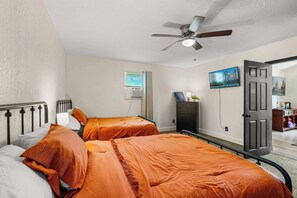 A bedroom with two beds, a ceiling fan, a TV, and a door leading to another room. - Stylish Loft Retreat, Near Disney, Sleeps 6 (Kissimmee)