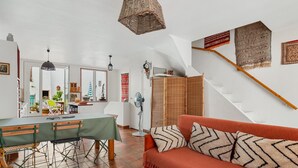 Ein Wohnzimmer mit einer Couch, einem Esstisch und einer Treppe mit einem Holzgeländer.