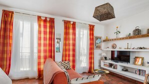 Ein Wohnzimmer mit einer Couch, Fernseher, Bücherregal und Dekorationselementen.