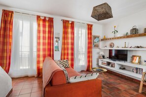 A living room with a sofa, television, bookshelf, and decorative items. - Patio Voltaire - A 5km de la plage (Sérignan)