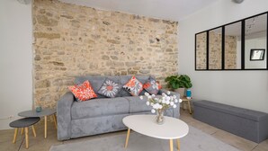 Ein Wohnzimmer mit Steinwand, grauem Sofa, weißem Couchtisch und einer Bank.