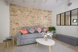 A living room with a stone wall, grey sofa, white coffee table, and a bench.