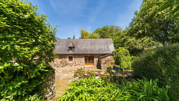 Una casa de piedra con techo inclinado, una puerta de madera y una ventana pequeña.