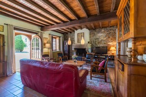 Ein gemütliches Wohnzimmer mit einem roten Sofa, Holzmöbeln, einer Steinwand, einem Kamin und einem Fernseher.