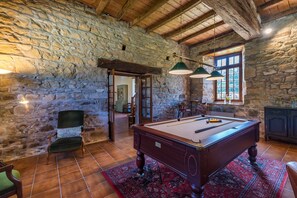 Ein Zimmer mit Pooltisch, einem Sessel, einer Lampe und einem Fenster mit Blick.
