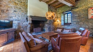 A stone-walled room with a fireplace, leather furniture, and a television. - Le Manoir - Plouguiel (Plouguiel)