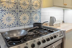 A kitchen with a gas stove, a frying pan, a kettle, and a coffee maker. - Spacious 3BR Home Near Burnley Town Centre (Lancashire)