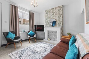 A modern living room with a fireplace, a television, and a sofa. - Spacious 3BR Home Near Burnley Town Centre (Lancashire)