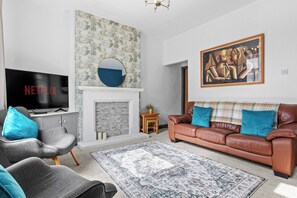 A living room with a fireplace, a television, a couch, and a rug. - Spacious 3BR Home Near Burnley Town Centre (Lancashire)