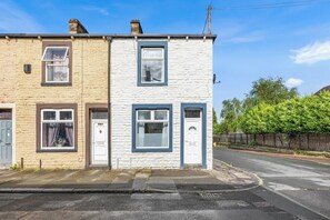 A two-story residential building with a white facade and blue trim. - Spacious 3BR Home Near Burnley Town Centre (Lancashire)