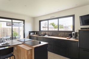 A modern kitchen with a large window, a built-in stove, and a dining area with a table and chairs. - La Villa Meunier - Four Bedroom House, Sleeps 7 (Dinard)