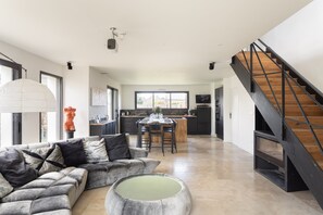 A modern living room with a sectional sofa, a coffee table, and a staircase. - La Villa Meunier - Four Bedroom House, Sleeps 7 (Dinard)