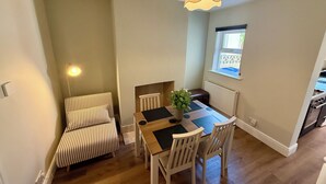 Spiseområde med et bord, stole, en stribet stol, en hængende lampe og et vindue med udsigt.