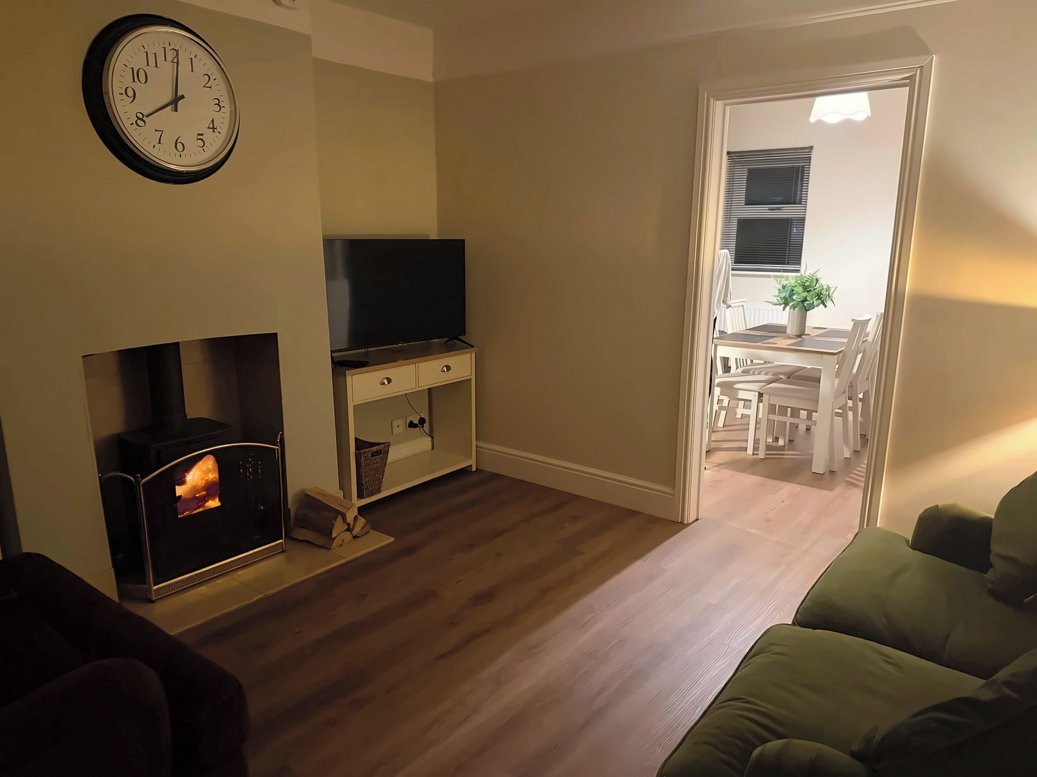 A living room with a fireplace, a television on a stand, and a dining area visible through an open door.