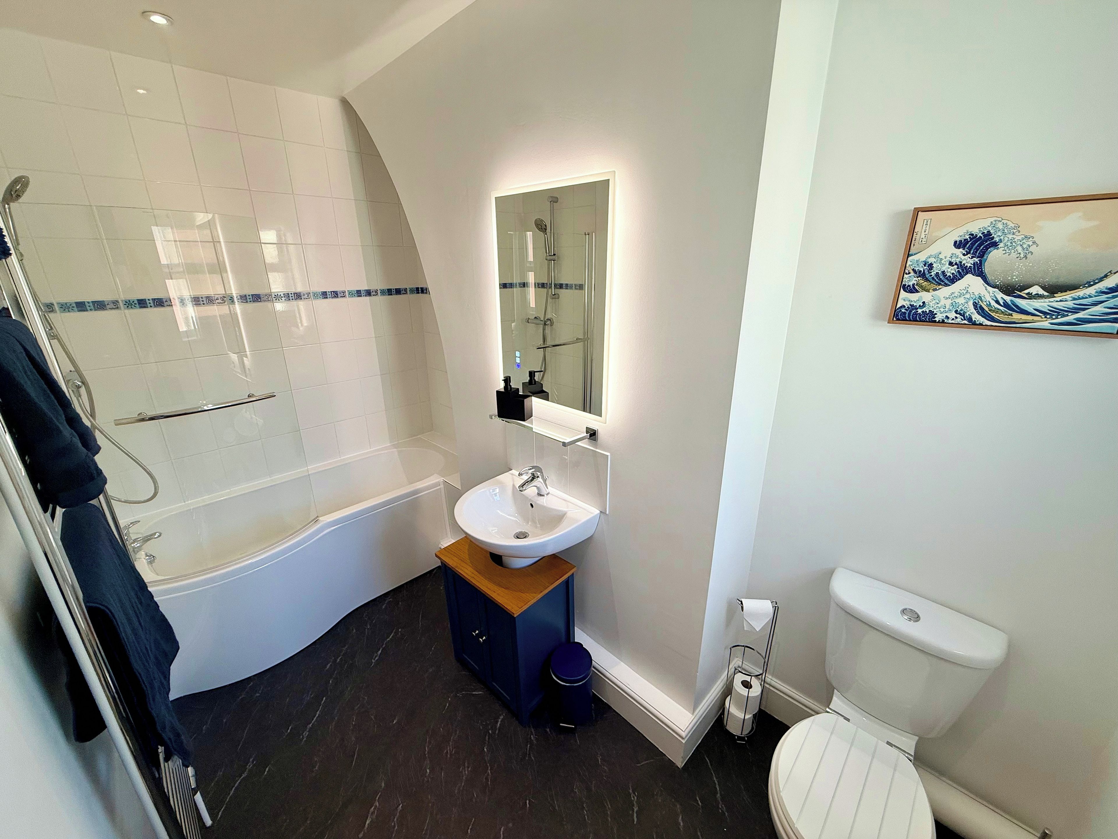 Bathroom with bath, shower and lit mirror