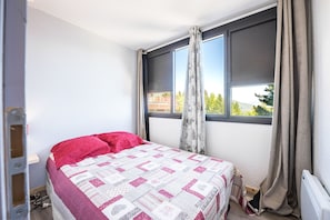 Ein Schlafzimmer mit Bett, Fenster und Heizkörper.