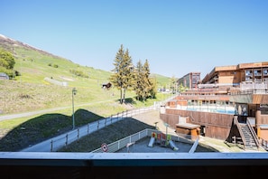 Ein Skigebiet mit einem Holzbau, einem Spielplatz und blauem Himmel.