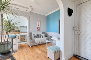 A living room with a sofa, a coffee table, a potted plant, and a wall with a picture. - Les Toits Lumineux de Vincennes - Proche château (Vincennes)