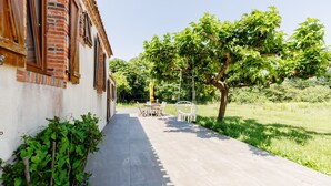 A pathway leading to a building with a brick facade and a garden area with a table and chairs. - La Chaumière de Jeannot - Maison avec jardin pour 8 (La Chapelle-Hermier)